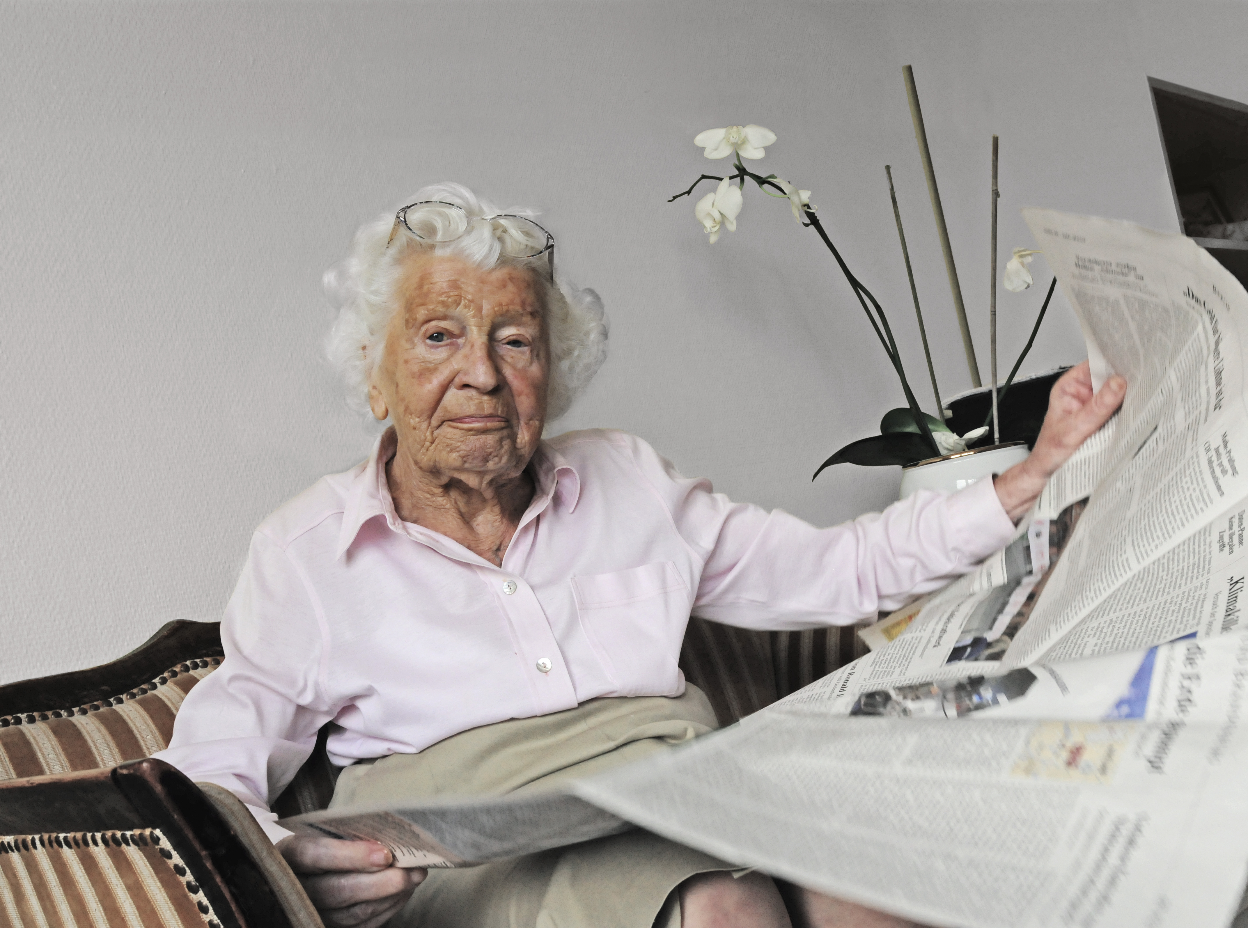 Das Foto zeigt eine ältere Frau, die Zeitung liest