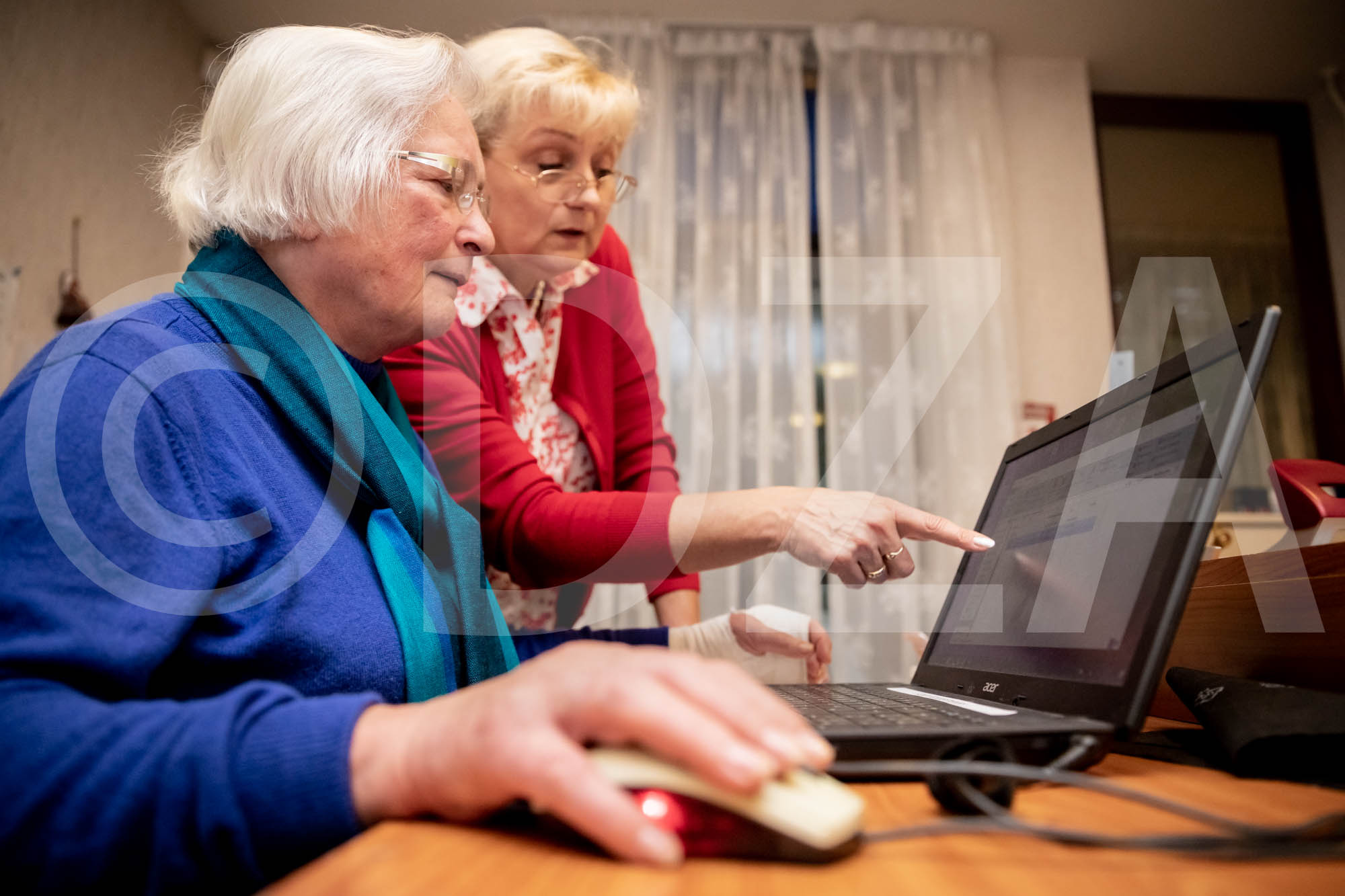 Zwei ältere Frauen betrachten zusammen den Bildschirm eines Laptops